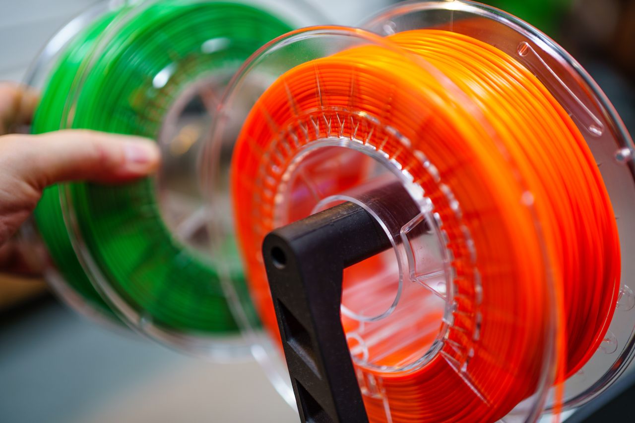 about-bg Vibrant orange and green 3D printer filament spools for innovative manufacturing uses.