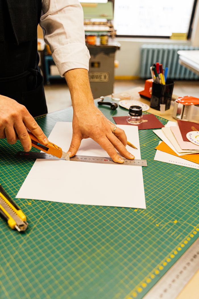 Close-up of hands cutting paper with precision tools in a creative workshop.